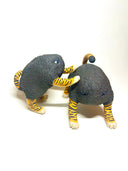 Two small sculptural cat figurines on a plain white studio background. Each cat has a dark charcoal body with bright orange and black tiger-like stripes on the legs, paws, and tail, plus small blue eyes.