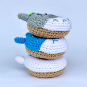 Stack of 3 crocheted donuts fashioned to look like characters from My Neighbor Totoro on their frosted side.