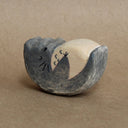 Wooden sculpture of a sleeping Totoro, seen from the side. It rests on its back which is curved, allowing it to rock back and forth. Its hands are on its stomach.