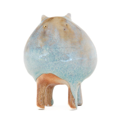 Ceramic sculpture of a character with a rounded body with blue liquid glaze down it. It has small ears and eyes and stands on 4 legs.
