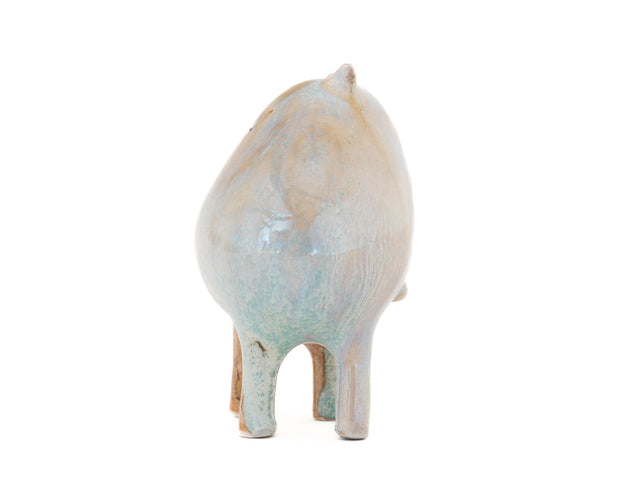 Ceramic sculpture of a character with a rounded body with blue liquid glaze down it. It has small ears and eyes and stands on 4 legs.