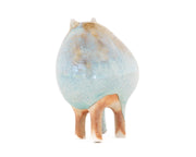 Ceramic sculpture of a character with a rounded body with blue liquid glaze down it. It has small ears and eyes and stands on 4 legs.