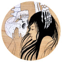 Illustration on circular wooden panel of a woman with long, wispy hair looking at an upside down skeleton with both of them caressing one another's face.