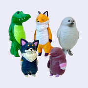 5 animal figurines, all standing on 2 legs and looking with blank expressions. Animals are: crocodile, fox, seal, fluffy Chihuahua and mole.