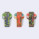 Three cups with colorful packaging on a light gray background, with Japanese text on them identifying the different herbs within each.