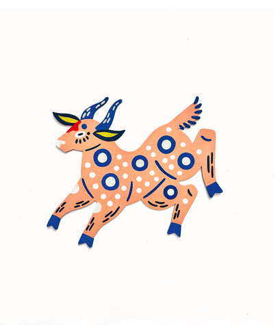 Die cut, brightly painted wooden sculpture of a folklore style deer, peach colored with dark blue and white polka dot patterns.