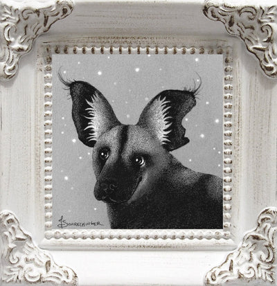 Softly rendered graphite drawing of a dog with very large ears, mostly black with some lighter areas. It looks up happily. Its framed in an ornate white frame.