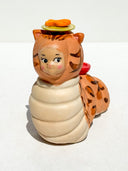 Caterpillar with the face of a Kewpie baby and coloring of a bengal cat. Atop its head is a green plate with an orange fish on it.