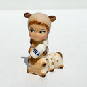 Caterpillar with the face of a Kewpie baby and coloring of a Siamese cat. It holds a bottle of milk in its hands.