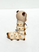 Caterpillar with the face of a Kewpie baby and coloring of a Siamese cat. It holds a bottle of milk in its hands.