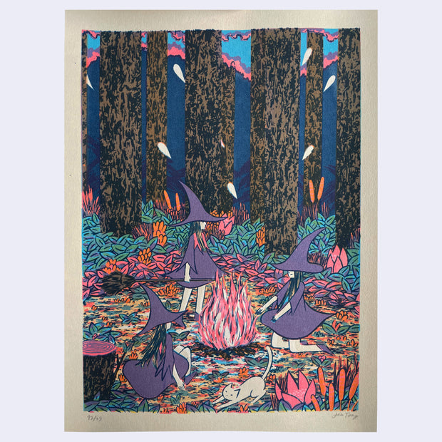Colorful print of 3 witches in purple hats and dresses standing around a forest bonfire.
