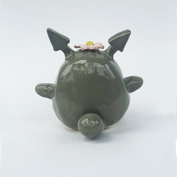 Ceramic figurine of a stylized Totoro with a flower on its head against a white background