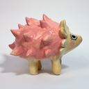 Ceramic sculpture of a cartoon style hedgehog with pink spikes and cute eyes and rosy cheeks.
