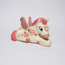 Ceramic figurine of a white horse with a pink mane and pink wings. It sits on the ground with its legs folded under it with red tattoos all over it.