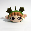 Ceramic head figurine of a girl's head with brown hair, earrings and rosy cheeks. She has a green hood hat with fin-like shapes coming out of it.