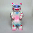 Sculpture made to look like a vinyl Kaiju cat - mostly white in color with spray paint colors of pink, blue and purple.