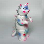 Sculpture made to look like a vinyl Kaiju cat - mostly white in color with spray paint colors of pink, blue and purple.