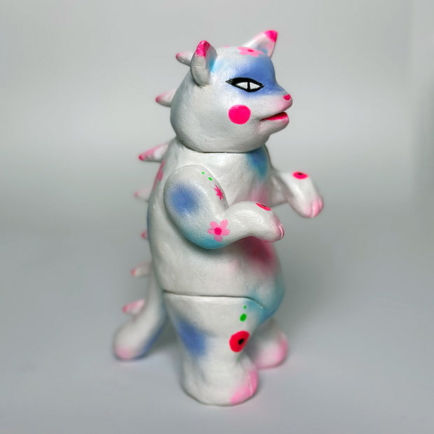 Sculpture made to look like a vinyl Kaiju cat - mostly white in color with spray paint colors of pink, blue and purple.