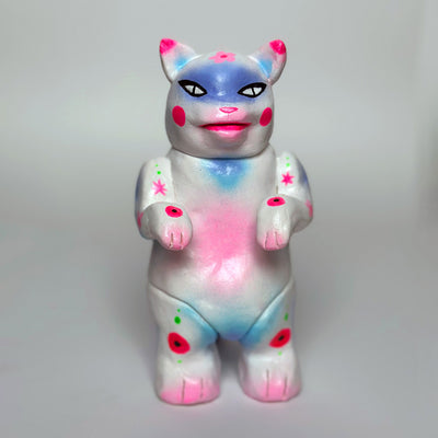 Sculpture made to look like a vinyl Kaiju cat - mostly white in color with spray paint colors of pink, blue and purple.