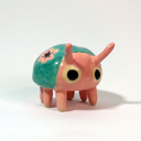 Small ceramic sculpture of a cute pink and teal bug.