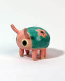 Small ceramic sculpture of a cute pink and teal bug.