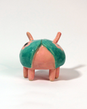 Small ceramic sculpture of a cute pink and teal bug.