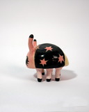 Small ceramic sculpture of a pink and black bug with a cute cartoon face.