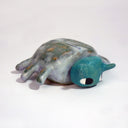 Ceramic sculpture of a cartoon beetle, with a teal head and large cartoon style eyes. Its body is a grayish green with dots.