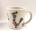 White mug with illustrated motifs of nature and birds.