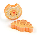 Set of 2 sponges themed on bread. One sponge is shaped like a croissant and the other is shaped like an everything bagel with a bite taken out of it.