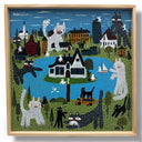 Framed artwork of several stylized cats, very large in size and tormenting a town around a lake. One house sits in the middle of the lake.