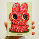 Illustration on light green paper of a cute cartoon bunny with very large eyes and a tiny nose and smile. Its body is made up of pink and red doodles of flowers, mushrooms and skulls. The bunny stands on its hind legs and looks up and to the side.