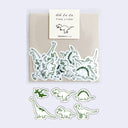 Pack of dinosaur-themed stickers with a brand label on a beige background
