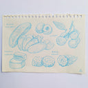 Sheet of paper with blue line drawings of various fruits and vegetables on a light purple background.