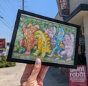 Colorful illustration of various kaiju monster creatures in a forest setting, walking in a line like Where the Wild Things Are. Piece is framed in someone's hand.