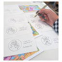 Hand holding a pen over printed designs on a table