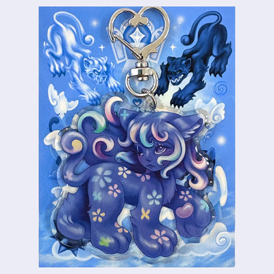 Acrylic keychain of a fantasy style cat creature with the face of a young girl, attached to metal hardware with a heart shaped clasp.