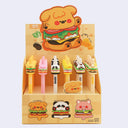 Display of cartoon-themed pens in a decorative box on a light gray background