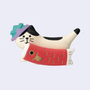 Figurine of a white cat with black spots, carrying a red carp windsock. It has a teal and purple hat on its head.