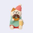 Cute figurine of a cat holding a donut and a cup on a light gray background