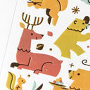 Illustrations of a deer, bear, and other animals on a white background, close up to show gold detailing.