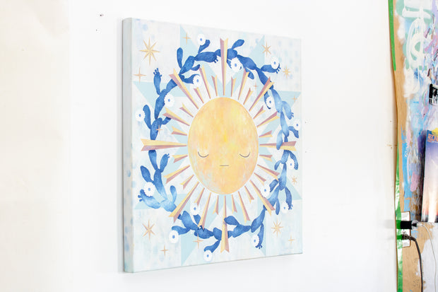 Painting of a yellow sun with graphic style rays coming off of it. A wreath of blooming cacti surround the sun. Background is painted white and blue like a quilt style pattern.