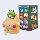 Cartoonish animal figurine with a smaller green character on top, next to a box featuring images of similar characters.