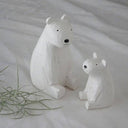 Two white polar bear figurines on a light gray background
