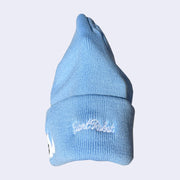 Side detailing of a light blue beanie with white embroidered cursive that reads "giant robot"