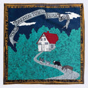 A square printed textile or scarf-style product featuring a stylized rural scene: a white house with a red roof sits on a winding gray path surrounded by teal trees, with a dark blue sky, white banners reading 'The Bremen Town Musicians' and a decorative gold-and-black border.