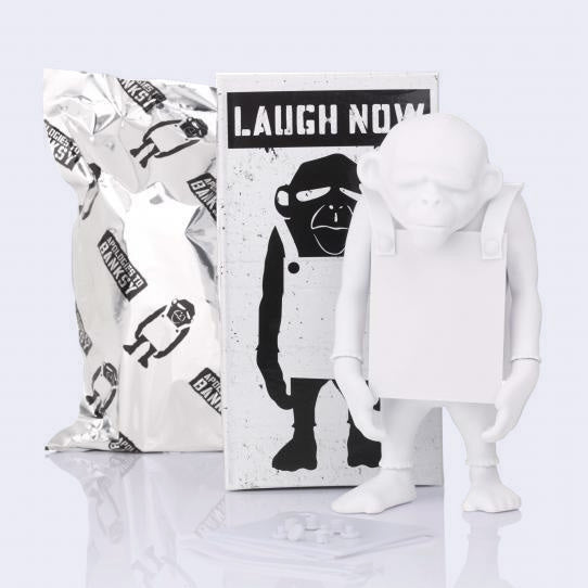 White figurine of a monkey wearing a sign - with a black and white box labeled 'Laugh Now' on a light gray background