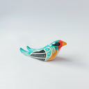 Glossy, painted ceramic sculpture of a barn swallow bird, sitting with its turquoise and black wings at its side. It has a yellow stomach and black and red face with a yellow beak.