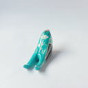 Glossy, painted ceramic sculpture of a barn swallow bird, sitting with its turquoise and black wings at its side. It has a yellow stomach and black and red face with a yellow beak.