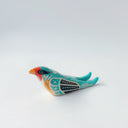 Glossy, painted ceramic sculpture of a barn swallow bird, sitting with its turquoise and black wings at its side. It has a yellow stomach and black and red face with a yellow beak.